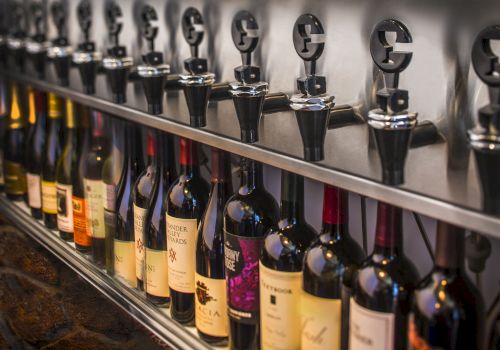 A row of wine bottles placed in a wine dispensing system, designed for serving wine by the glass while maintaining its freshness.